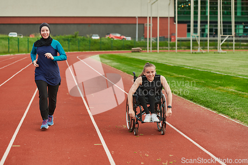 Image of A Muslim woman in a burqa running together with a woman in a wheelchair on the marathon course, preparing for future competitions.