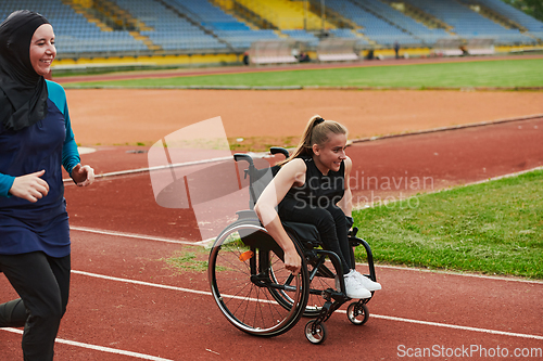 Image of A Muslim woman in a burqa running together with a woman in a wheelchair on the marathon course, preparing for future competitions.