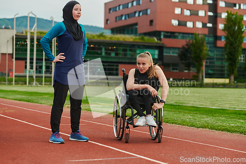 Image of A Muslim woman wearing a burqa resting with a woman with disability after a hard training session on the marathon course