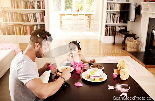 Image of Heres a cookie for you too Dad. Shot of a father and his little daughter having a tea party together at home.