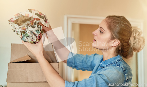 Image of Making sure her valuables are snugly packed. Shot of a young woman unpacking a box at home.