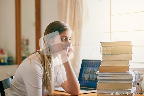 Image of Thats an overwhelming amount of information. Shot of a young woman looking overwhelmed by the pile of books on her desk.