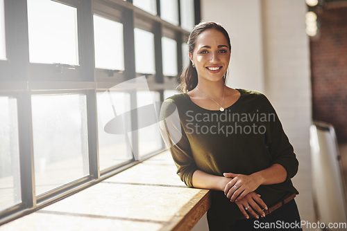 Image of Self-confidence is everything if you want to become successful. Portrait of a confident young businesswoman standing at a window in an office.