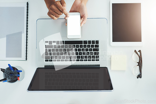 Image of Staying in the loop with the touch of a button. High angle shot of an unrecognizable woman sitting at her office desk scrolling through her smartphone.