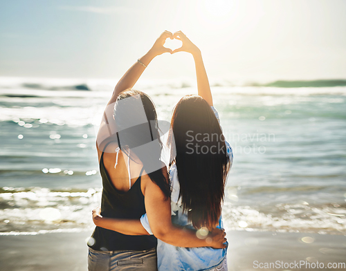 Image of We share a love for beautiful things. Rearview shot of two friends forming a heart shape together on the beach.