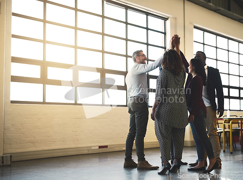 Image of We feel good about the work we do. Shot of a diverse team of happy businesspeople high fiving each other in the office.
