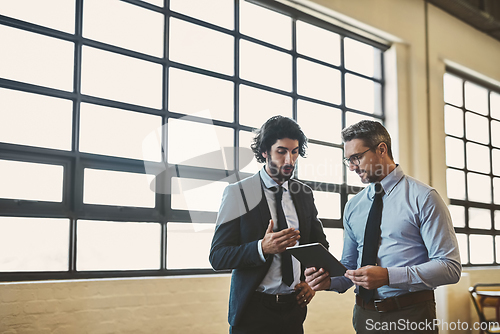 Image of I think youre off to a good start. Shot of two well-dressed businessmen brainstorming together over a tablet in their office.