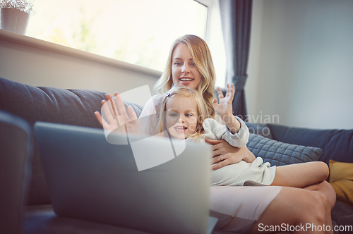 Image of Wave hello to nana. Shot of an adorable little girl using a laptop with her mother on the sofa at home.