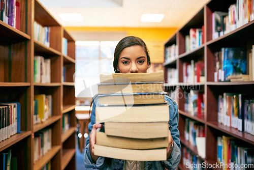 Image of Its a stack of knowledge. Portrait of a university student holding a pile of books in the library at campus.