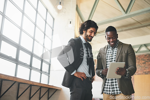 Image of Check out this cool app I found. Shot of two well-dressed businessmen brainstorming together over a tablet in their office.