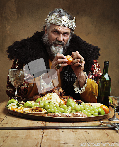 Image of Its good to be the king. A mature king feasting alone in a banquet hall.