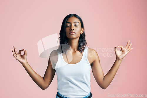 Image of Namaste. Studio shot of a beautiful young woman meditating against a pink background.