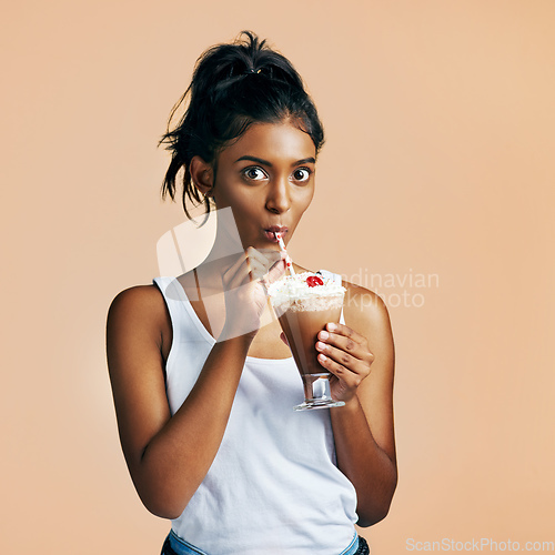 Image of Milkshake is my favourite. Studio portrait of a beautiful young woman posing with a chocolate milkshake against an orange background.