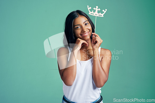 Image of The cutest queen ever. Studio portrait of a beautiful young woman posing with a prop crown against a green background.