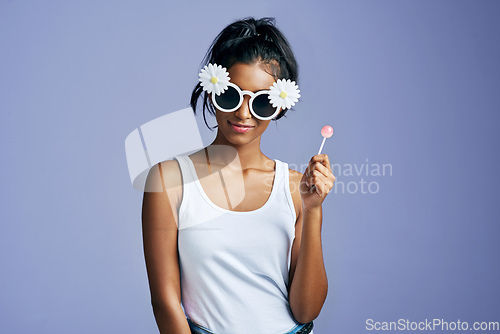 Image of Sweet style. Studio portrait of a beautiful young woman sucking on a lollipop against a purple background.