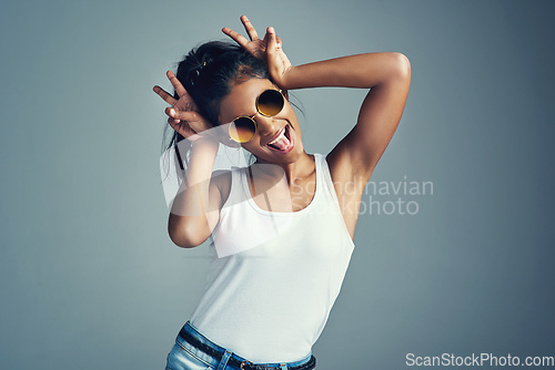 Image of Showing off her quirky side. Studio portrait of a beautiful young woman gesturing with bunny ears against a grey background.