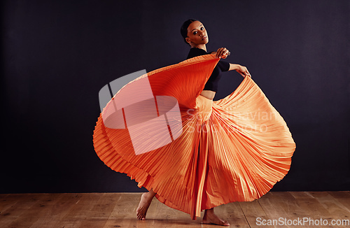 Image of Exotic expression. Female contemporary dancer in a dramatic pose against dark background.