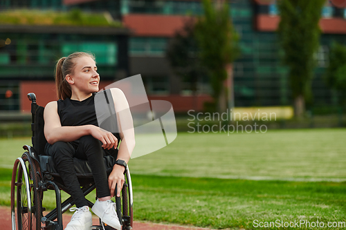 Image of A smiling woman with disablitiy sitting in a wheelchair and resting on the marathon track after training