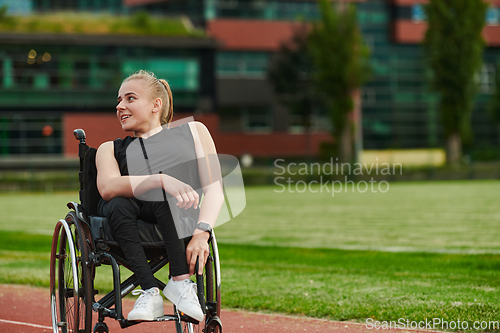 Image of A smiling woman with disablitiy sitting in a wheelchair and resting on the marathon track after training