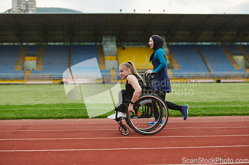 Image of A Muslim woman in a burqa running together with a woman in a wheelchair on the marathon course, preparing for future competitions.