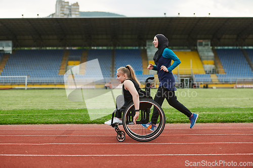 Image of A Muslim woman in a burqa running together with a woman in a wheelchair on the marathon course, preparing for future competitions.