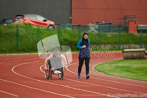 Image of A Muslim woman in a burqa running together with a woman in a wheelchair on the marathon course, preparing for future competitions.