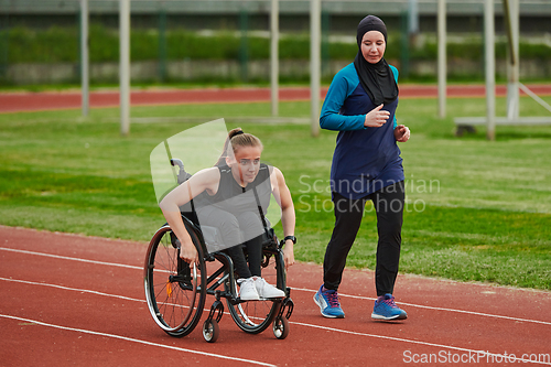 Image of A Muslim woman in a burqa running together with a woman in a wheelchair on the marathon course, preparing for future competitions.