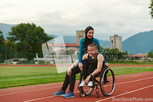 Image of A Muslim woman wearing a burqa resting with a woman with disability after a hard training session on the marathon course