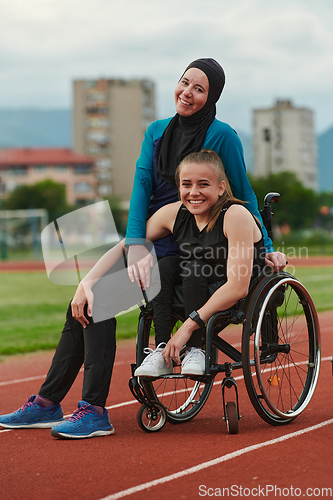 Image of A Muslim woman wearing a burqa resting with a woman with disability after a hard training session on the marathon course