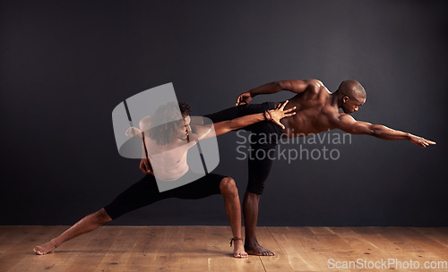 Image of The power of unified expression. Two male contemporary dancers performing a dramatic pose in front of a dark background.