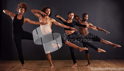 Image of Perfectly poised. A group of dancers performing a dramatic pose in front of a dark background.