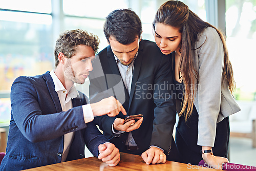 Image of Lets enjoy connectivity together. Cropped shot of businesspeople using a cellphone together indoors.