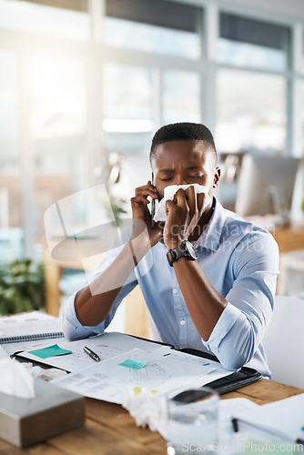 Image of Hes booking an appointment with the doctor right away. Shot of a sickly young businessman taking a phone call while covering his nose with a tissue in his office.