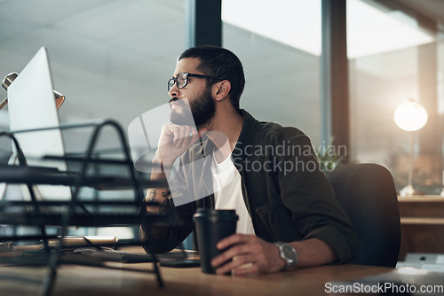 Image of Focus and consistency keeps you on task. Shot of a young businessman using a computer during a late night in a modern office.