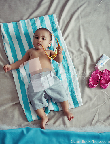 Image of Excuse me while I get my beach on. Concept shot of an adorable baby boy lying on a towel at a make believe beach.