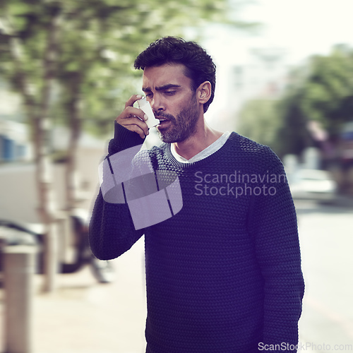 Image of Seeking relief from his wheezing chest. Cropped shot of a young man using his asthma pump outside.