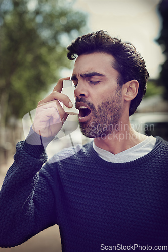 Image of Getting his symptoms under control. Cropped shot of a young man using his asthma pump outside.