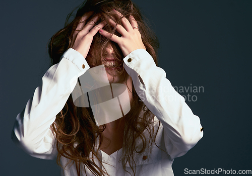 Image of Messy hair dont care. Studio shot of an unrecognizable woman covering her face with her hair against a blue background.