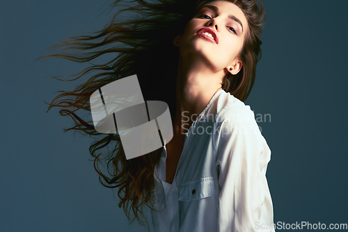 Image of Whip your hair back and forth. Studio shot of an attractive young fashionable woman posing against a blue background.