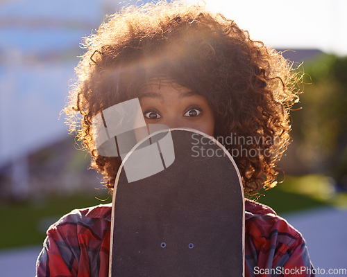 Image of A little fun in the skate park. A young woman with a quirky expression holding her skateboard.