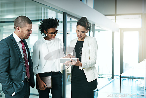 Image of I think we should go with this idea. Shot of a business team using a digital tablet while having an informal meeting.