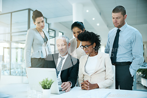 Image of Trying to convince his team to agree with him.... Shot of a group of businesspeople coming together to work on something on a laptop.