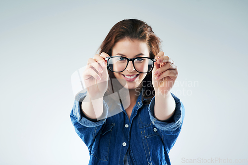 Image of I see you. Studio portrait of a young woman holding a pair of spectacles against a grey background.