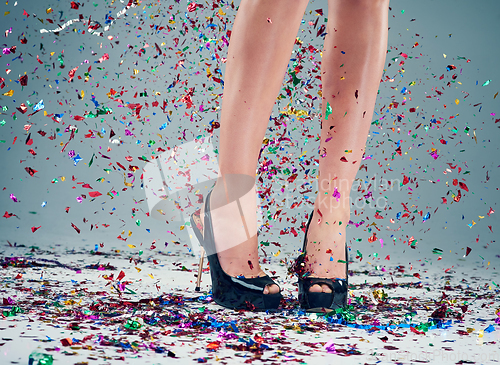 Image of Are you ready to party. Studio shot of a young womans legs in a pair of heels with confetti falling around against a grey background.