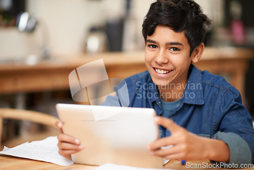 Image of Growing through online education. Portrait of a young teenage boy using a digital tablet while doing his homework.