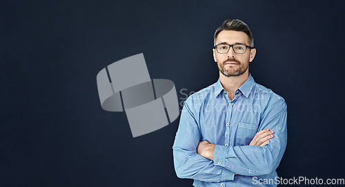 Image of Hes got character and confidence. Studio portrait of a handsome businessman standing with his arms folded against a dark background.