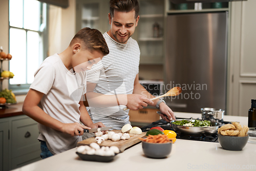 Image of Youre such a natural. Cropped shot of a young boy helping his father cook in the kitchen.