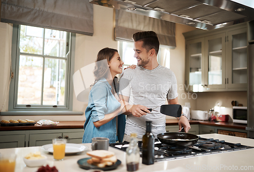 Image of Are you trying to score some brownie points. Shot of a young woman embracing her partner while he cooks breakfast.