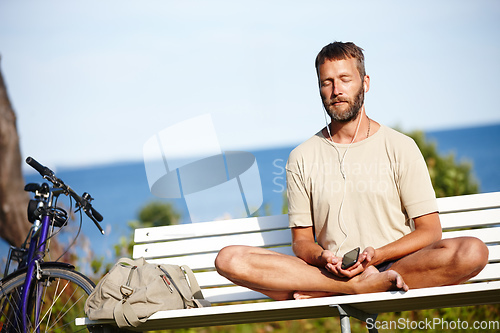 Image of He cycled to his place of calm. Shot of a mature man listening to music while doing a relaxation exercise outdoors.