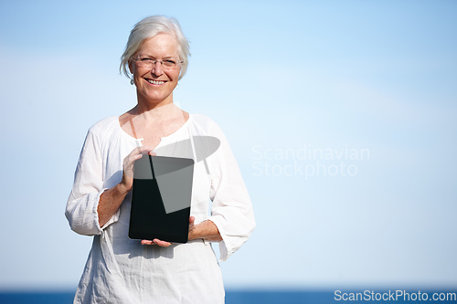 Image of Shes found some great relaxation exercises online. Portrait of a mature woman holding up a digital tablet while standing outside.